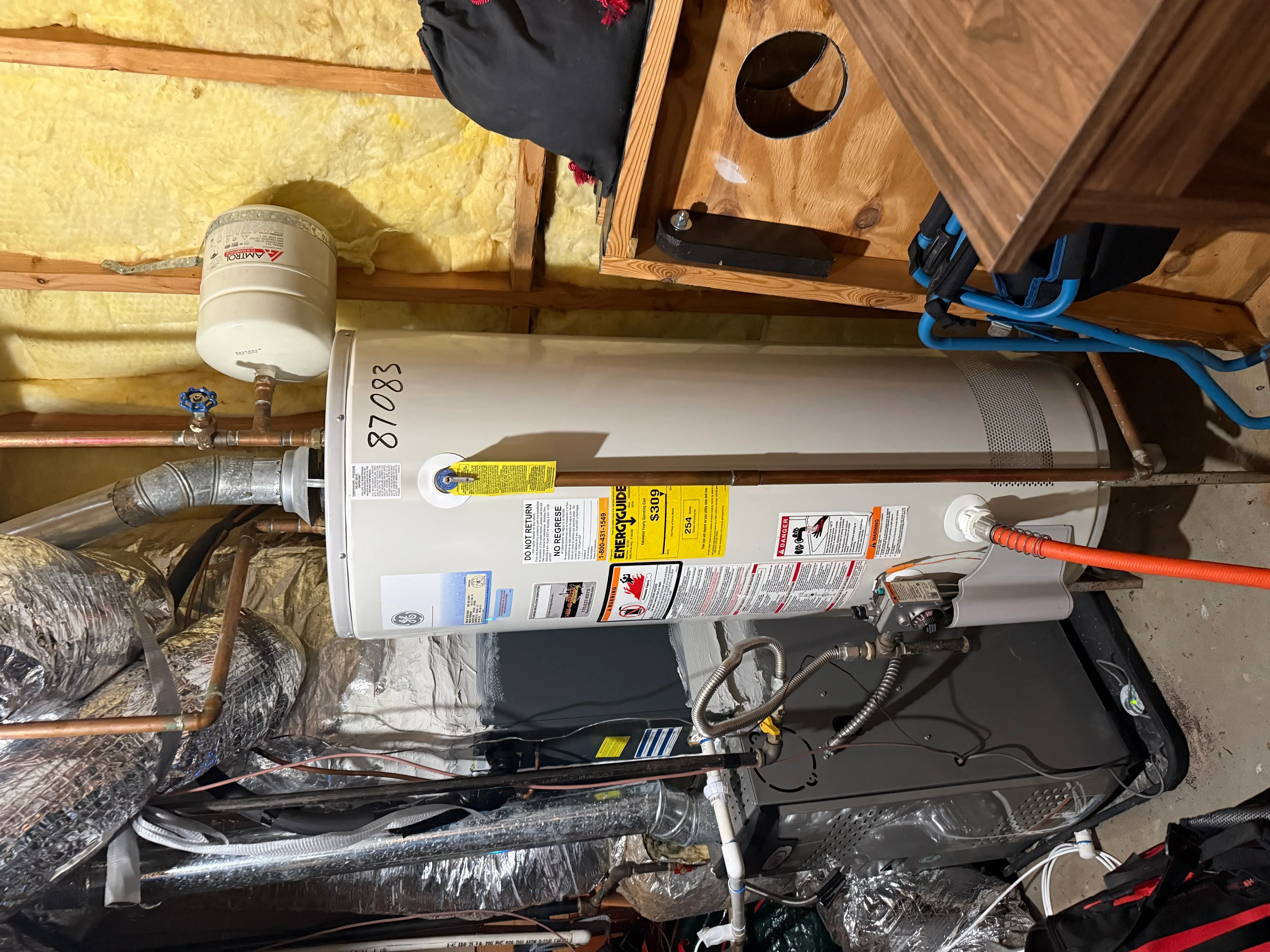 New water heater installation with copper piping and safety connections in attic
