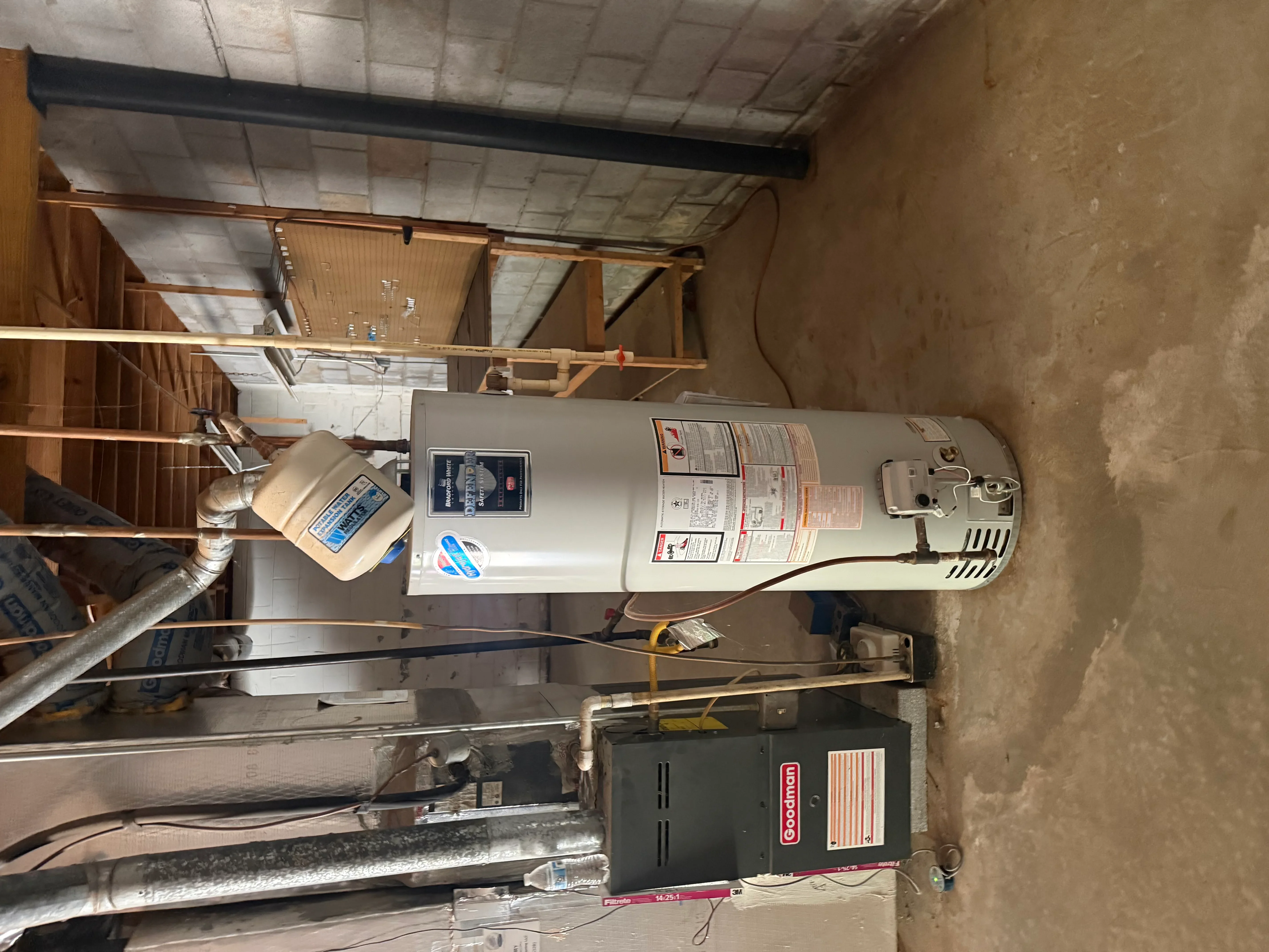Newly installed white cylindrical water heater with copper piping connections and electrical wiring in utility space